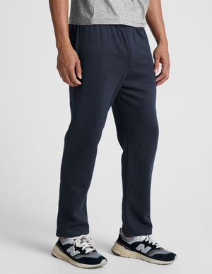 man wearing navy blue straight leg fleece sweatpants on a plain background. 
