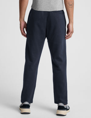 man wearing navy blue straight leg fleece sweatpants on a plain background. 