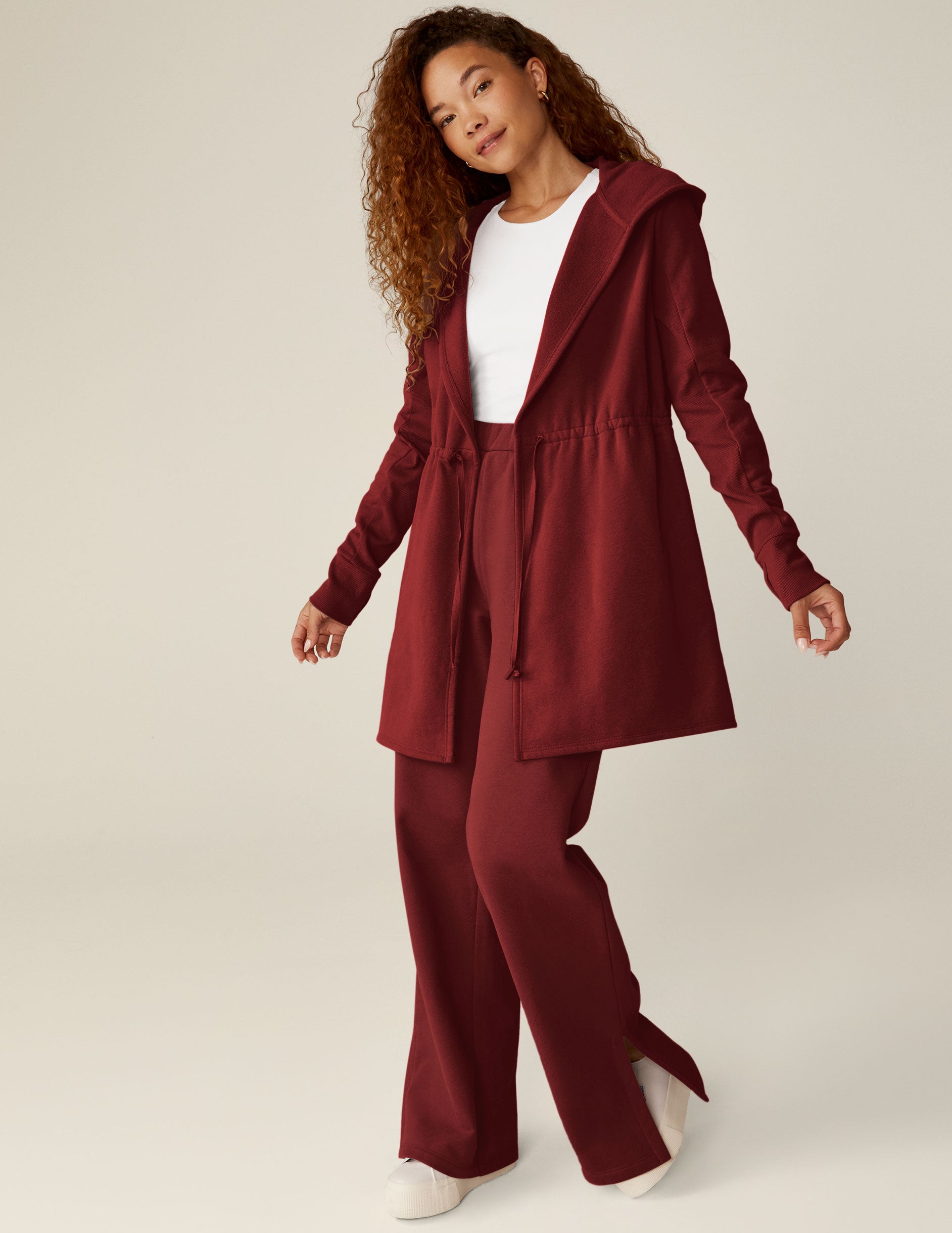 red long length hooded jacket with a drawstring at the waist and side pockets. 