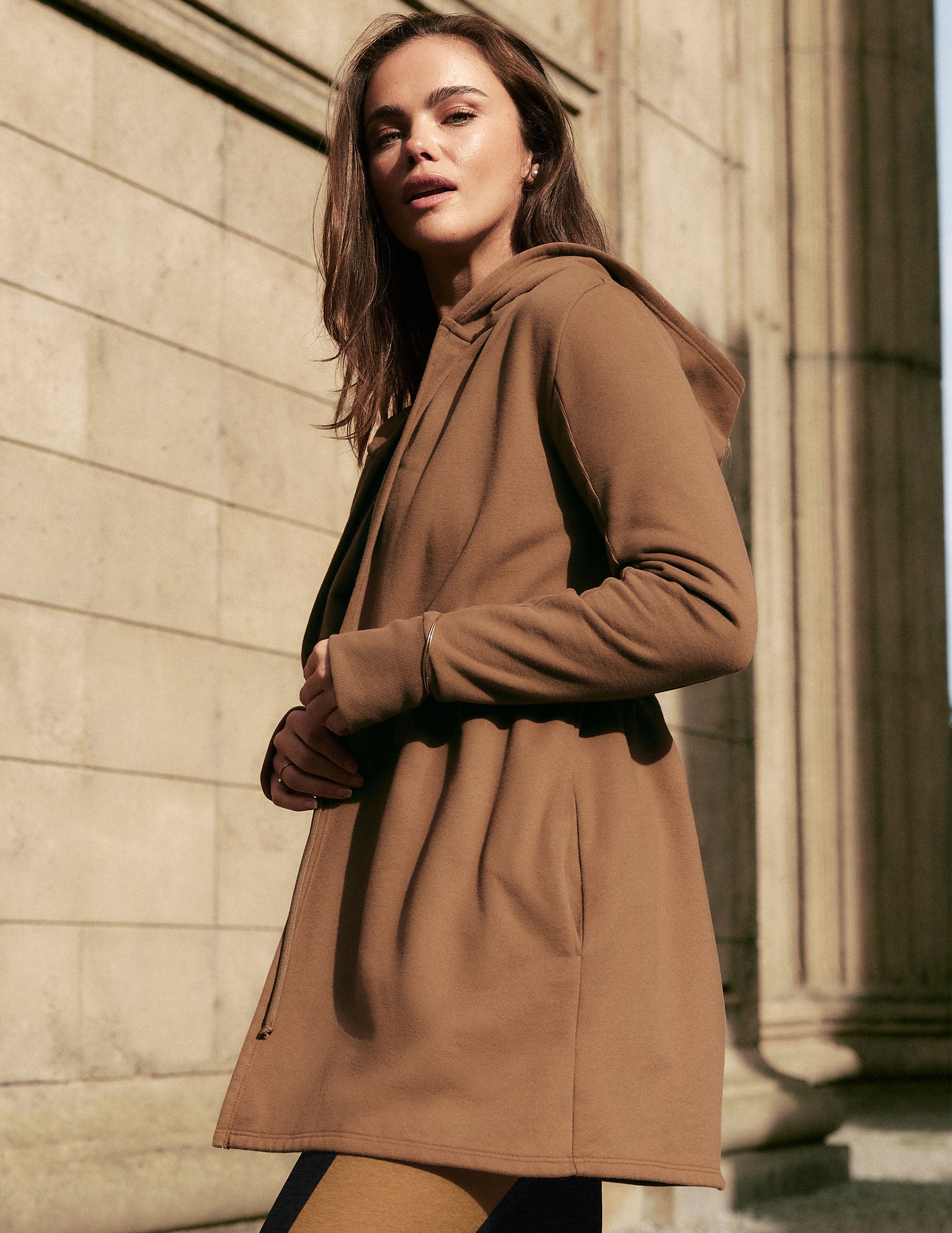 brown hooded jacket with a drawstring at the waist and thumb holes. 