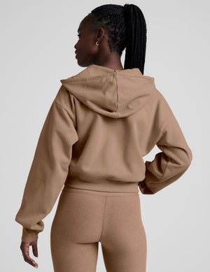model wearing a brown fleece zip-up hoodie and leggings set on a plain background. 