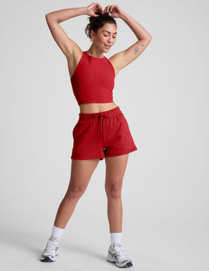 woman wearing a red sweat shorts against a plain background. 