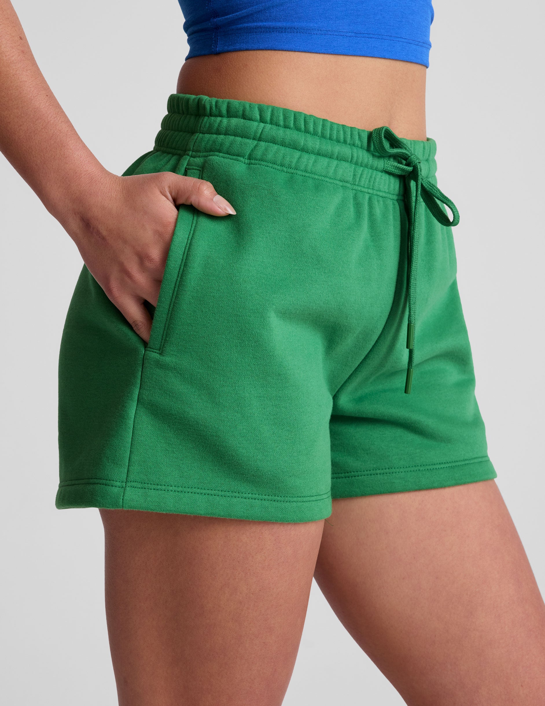 green sweat shorts with pockets and a drawstring at waistband. 