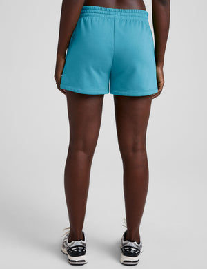 Person wearing bright blue shorts on a plain background. 