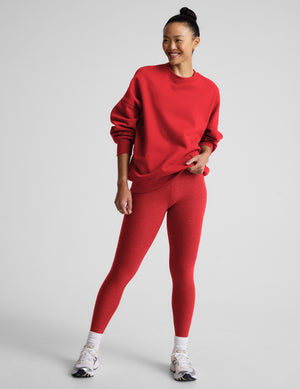 Woman wearing a red fleece sweatshirt and leggings against a light gray background. 