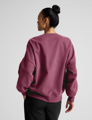 Woman wearing a pink oversized sweatshirt and black pants on a plain background. 