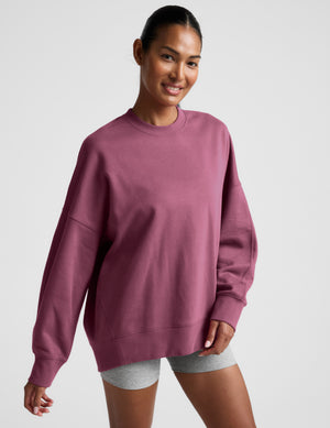 Woman wearing a mauve sweatshirt against a plain background. 