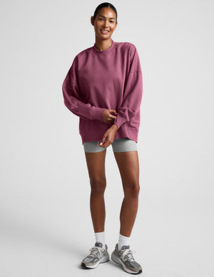 Woman wearing a mauve sweatshirt against a plain background. 