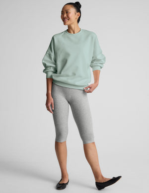 model wearing a light blue oversized crew neck fleece sweatshirt against a plain background. 