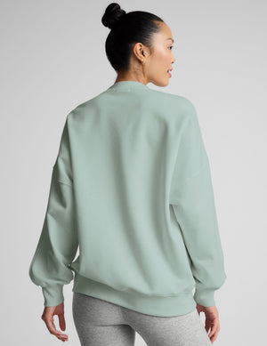 model wearing a light blue oversized crew neck fleece sweatshirt against a plain background. 