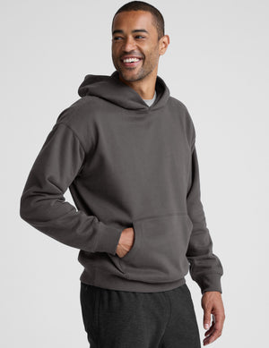 Man wearing a gray hoodie and pants on a light gray background. 