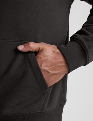man wearing a black hoodie on a plain background. 