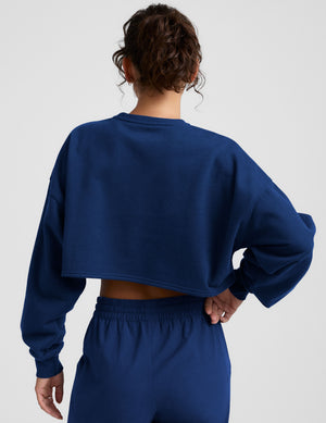 Woman wearing a blue sweatshirt and sweatpants on a plain background. 