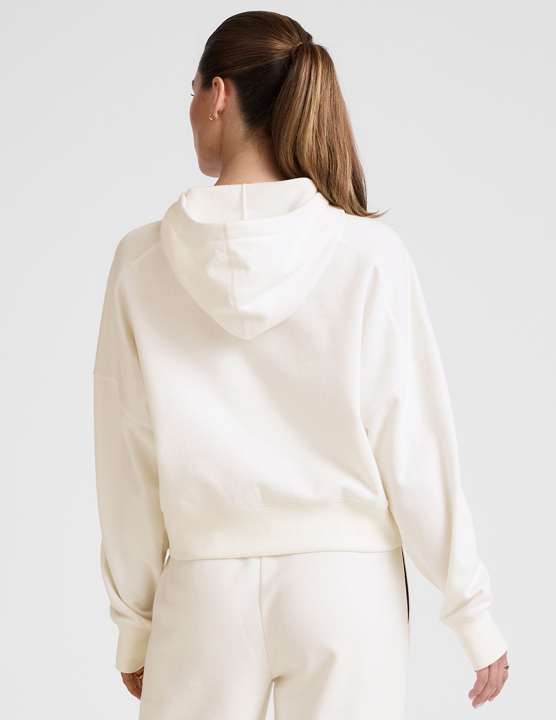 white cropped pullover with a hood with drawcord and a kangaroo pocket. 