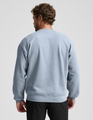 Man wearing a light blue sweatshirt on a plain background. 