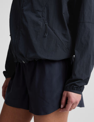 Woman wearing a blue hooded jacket and shorts against a plain background. 