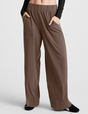 Woman wearing Brown Easy Wide Leg Pant™ with hands in pockets, paired with a black long-sleeve top.
