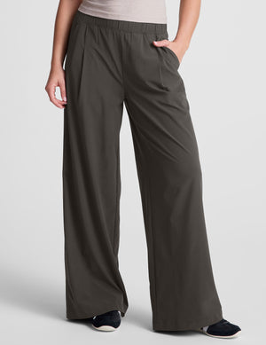 Front view of a person wearing gray Easy Wide Leg Pants with an elastic waist, front pleats, and hand in a side pocket.