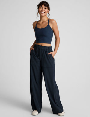 A smiling woman wears navy Easy Wide Leg Pants featuring a relaxed fit, elastic waistband, and front patch pockets.