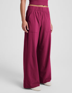 Woman wearing a magenta tank top and magenta wide leg pants against a plain background. 