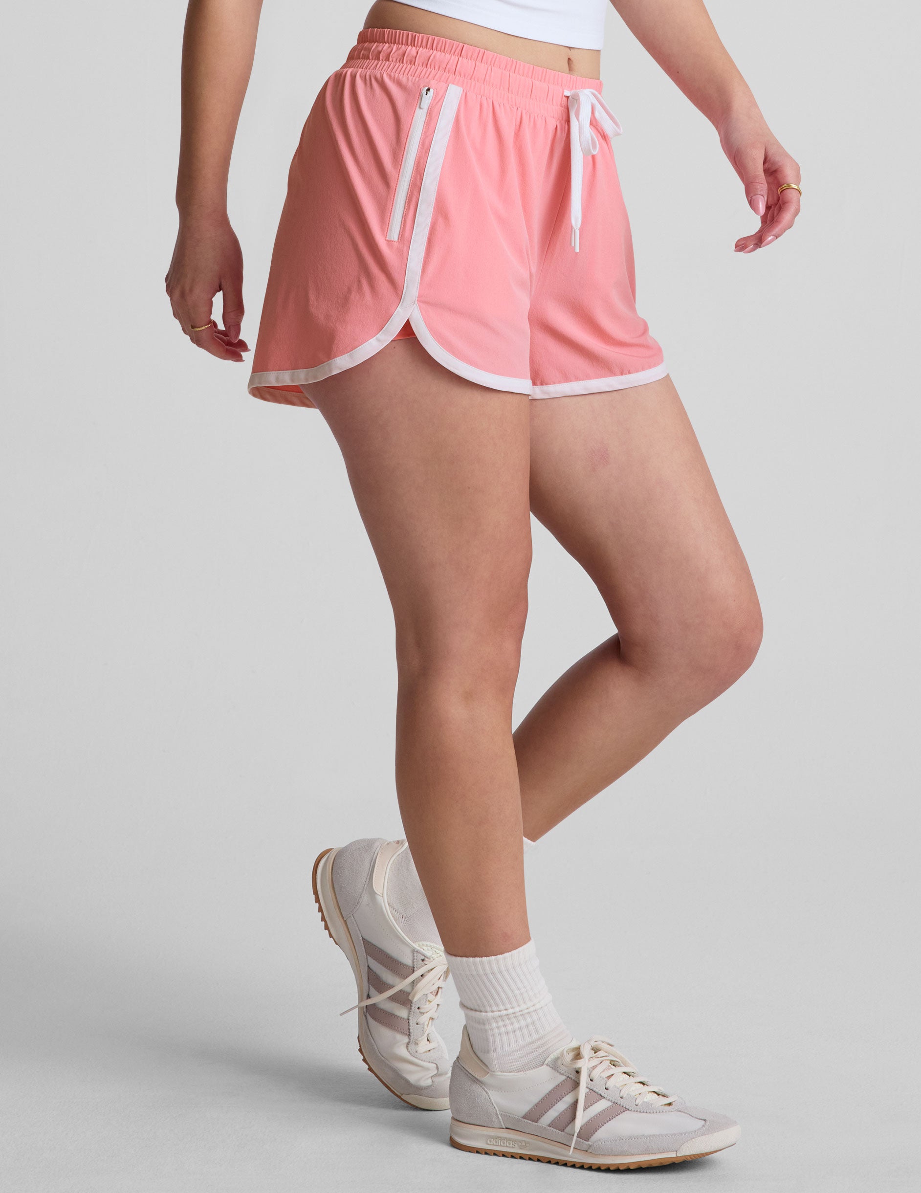 pink 2.5" inseam short with an encased elastic at waistband with drawcord​, self binding at hem edges​, side zipper pockets, and interior performance lining shorts​. 