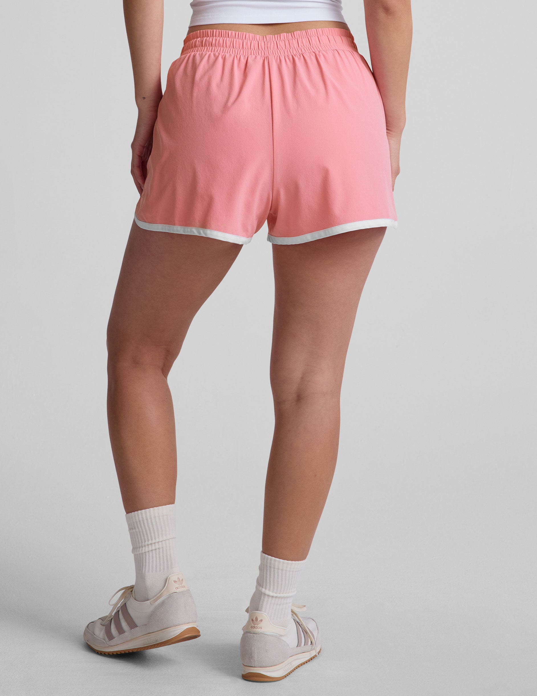 pink 2.5" inseam short with an encased elastic at waistband with drawcord​, self binding at hem edges​, side zipper pockets, and interior performance lining shorts​. 