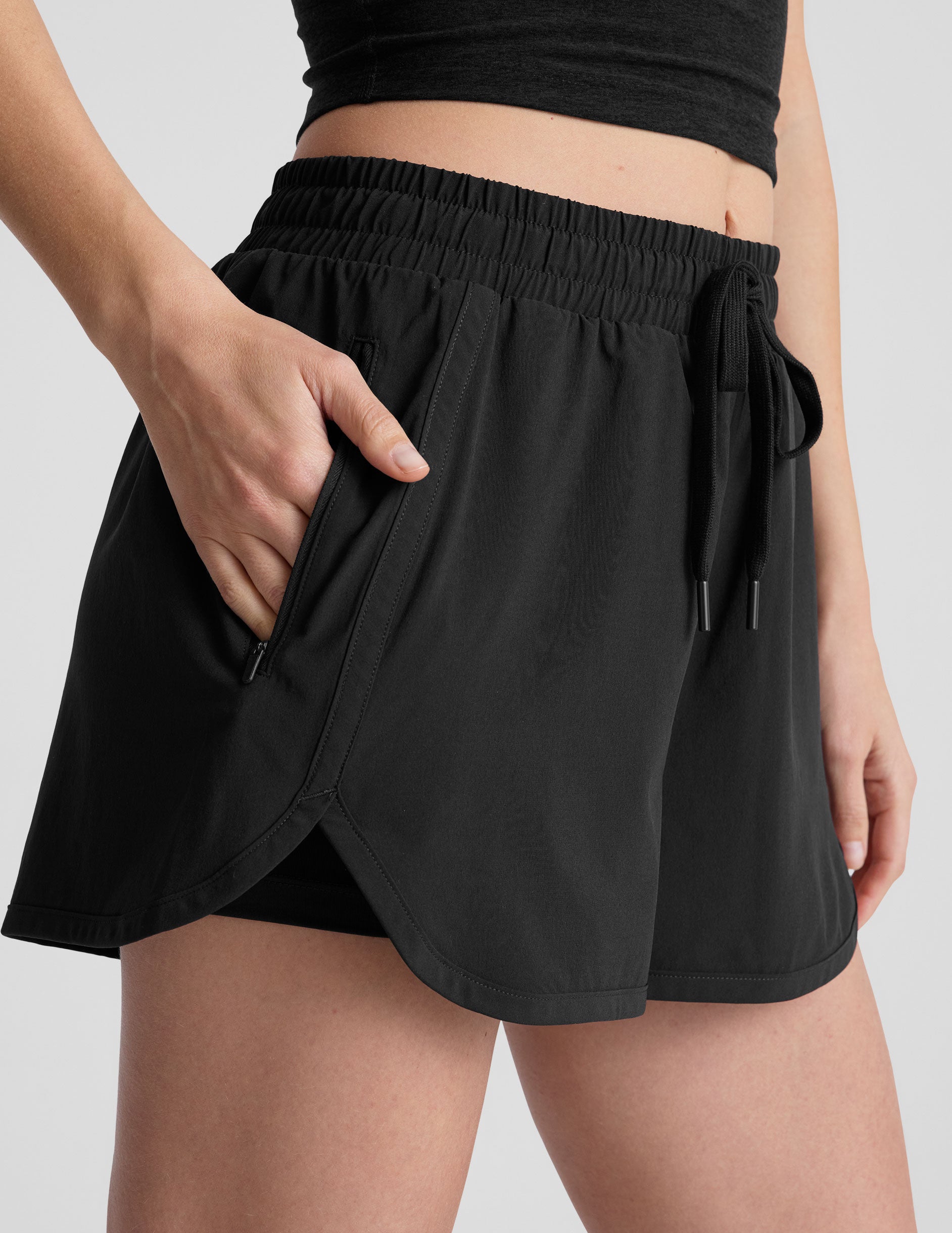 black shorts with a 2.5" inseam, encased elastic at waistband with drawcord​, self binding at hem edges​, side zipper pockets, and interior performance lining shorts​. 