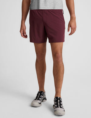 man wearing a grey t-shirt and maroon lined shorts set on a white background. 