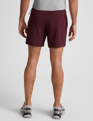 man wearing a grey t-shirt and maroon lined shorts set on a white background. 