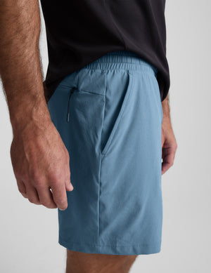 Man wearing light blue shorts against a plain background. 