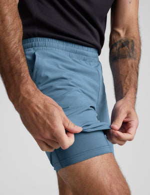 Man wearing light blue shorts against a plain background. 