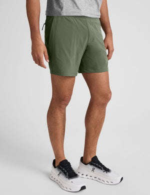 model wearing green men's lined shorts on a plain background. 