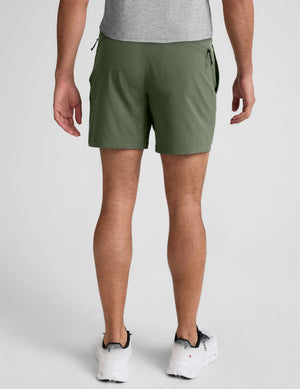 model wearing green men's lined shorts on a plain background. 