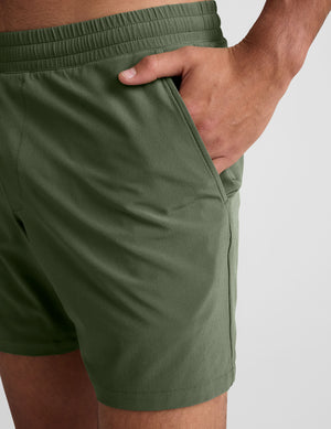 model wearing green men's lined shorts on a plain background. 