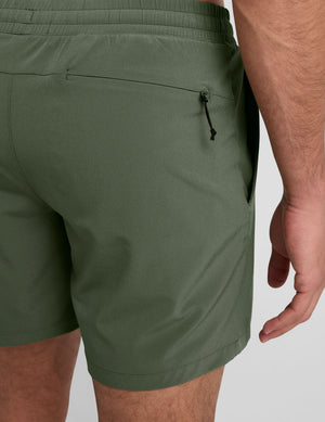 model wearing green men's lined shorts on a plain background. 