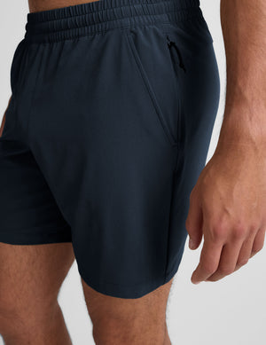 man wearing a navy t-shirt and blue shorts on a white background. 