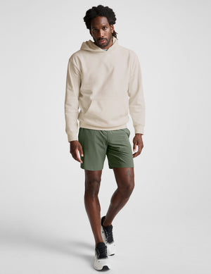 man wearing a white hoodie and green shorts on a white background. 
