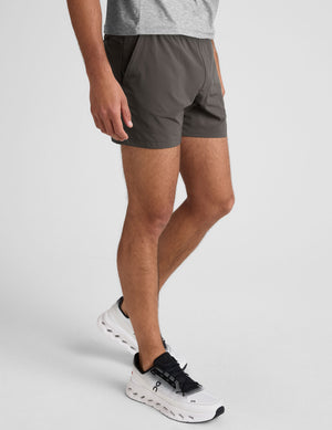man wearing a gray t-shirt and grey shorts on a plain background. 