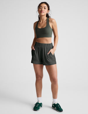 Woman wearing a green sports bra and shorts set on a plain background. 