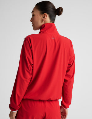 Woman wearing a red jacket with white accents against a plain background. 