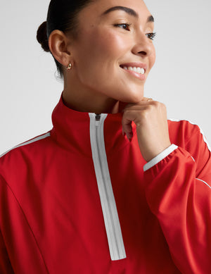 Woman wearing a red jacket with white accents against a plain background. 