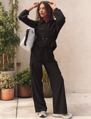Woman wearing black City Chic Cargo Pant with wide legs and cargo pockets in a stylish, casual outdoor urban setting.