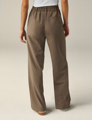 Back view of brown Status Wide Leg Trousers featuring an elastic waistband, belt loops, and a relaxed wide-leg silhouette.