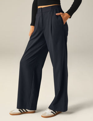 Status Wide Leg Trousers in black with front pleats and side pockets, featuring an elastic waistband and relaxed drape.
