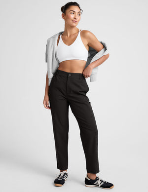 Model wearing black Status Tapered Pant with mid-rise waist and tapered leg, styled with white sports bra and sneakers.