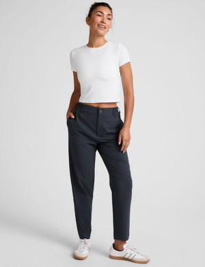 Model in white tee and dark Status Tapered Pant with belt loops, button fly, and seam pockets, paired with white sneakers.