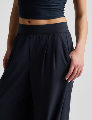 Woman wearing a blue cropped t-shirt and blue elasticated trouser pants against a plain background. 