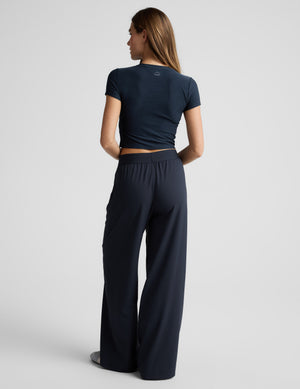 Woman wearing a blue cropped t-shirt and blue elasticated trouser pants against a plain background. 