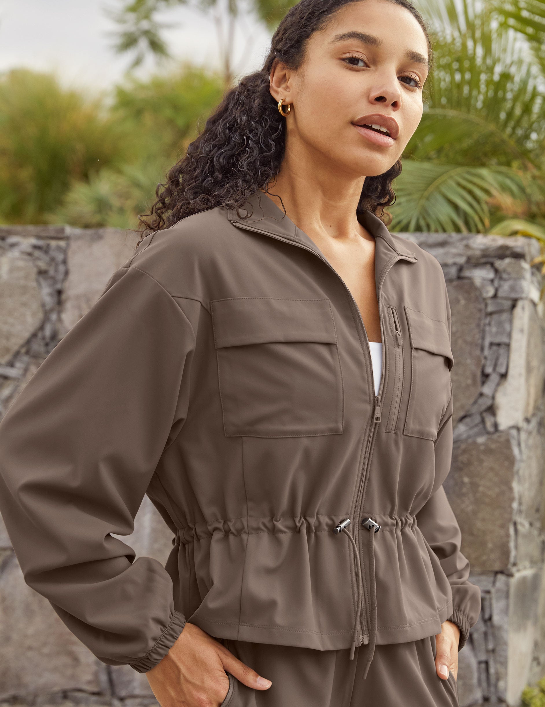 brown cargo style zip-up jacket with a drawstring tie at waist and pockets. 