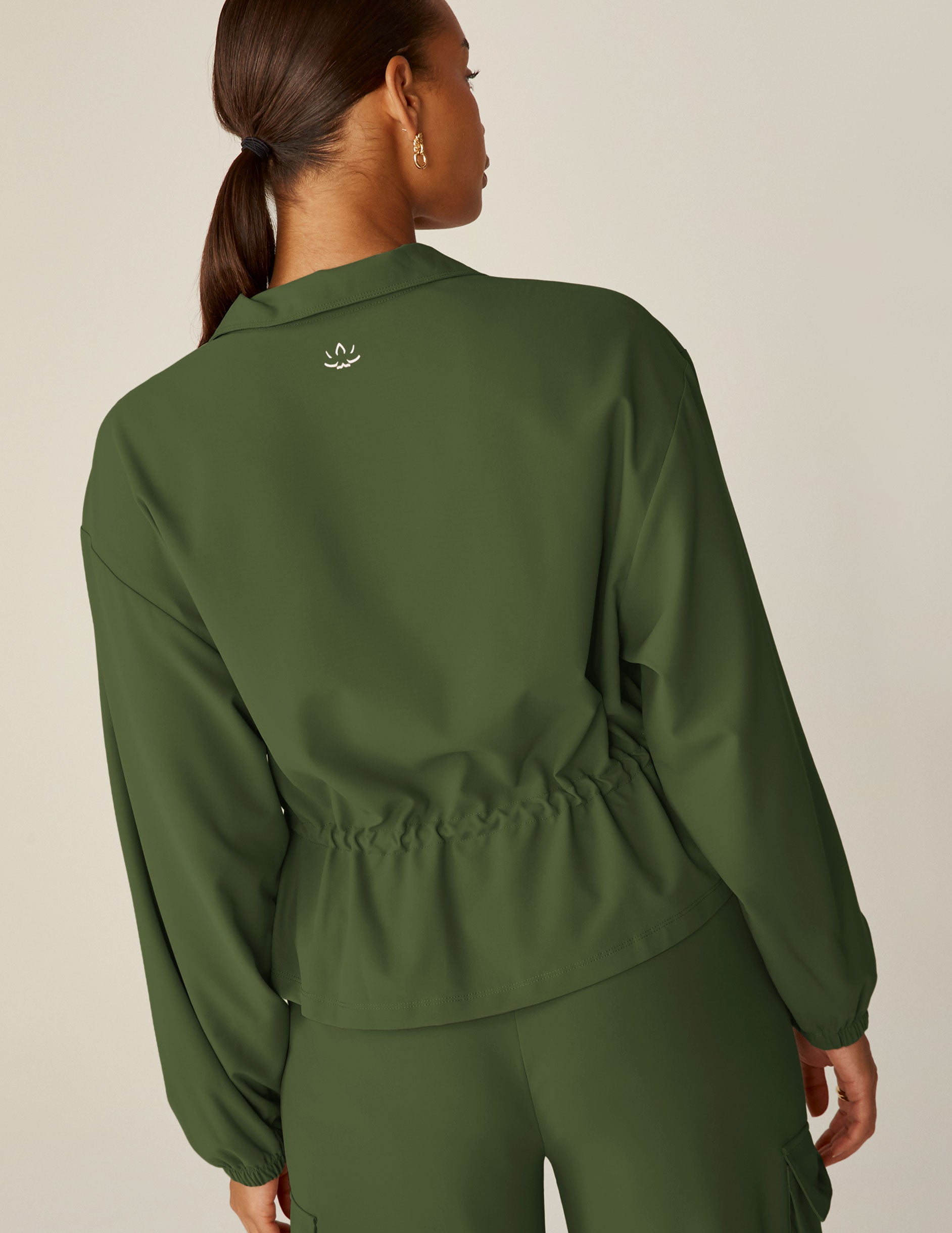green zip-up jacket with a drawstring at waistband and cargo style pockets.